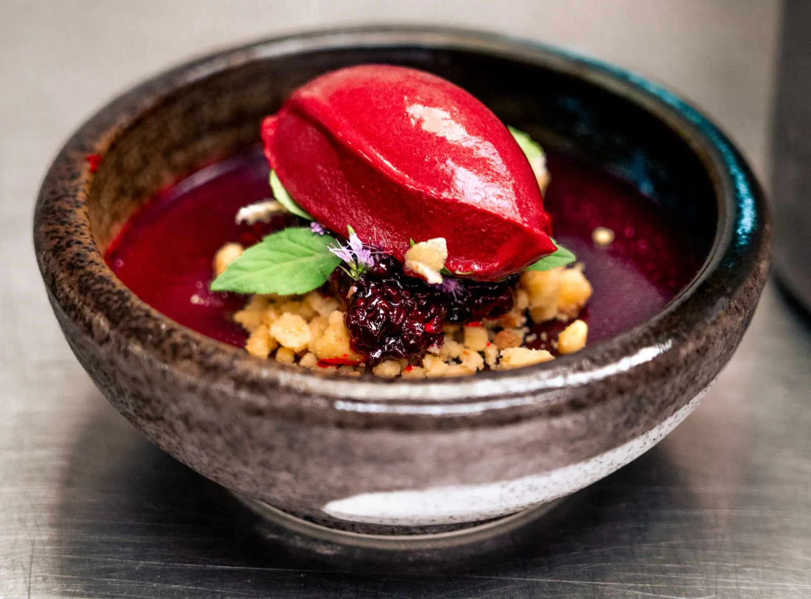 A delectable berry sorbet served in a rustic bowl, garnished with fresh mint and crumble.